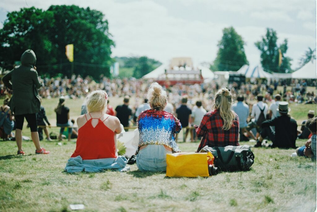 Drie vrouwen zitten op het grasveld bij een festival